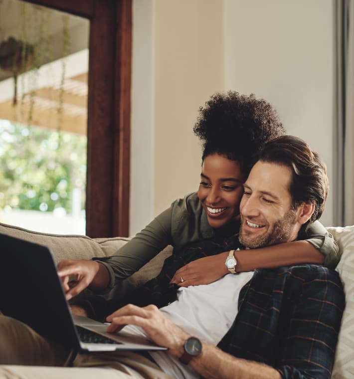 Couple on couch viewing laptop