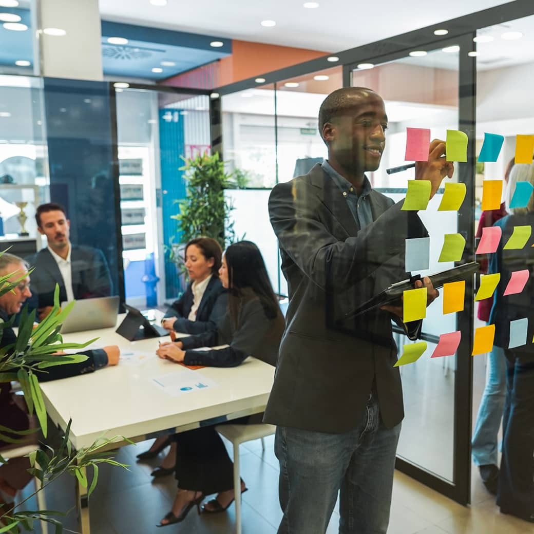 Man putting post it notes on conference room wall